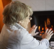 old lady warming hands near fire
